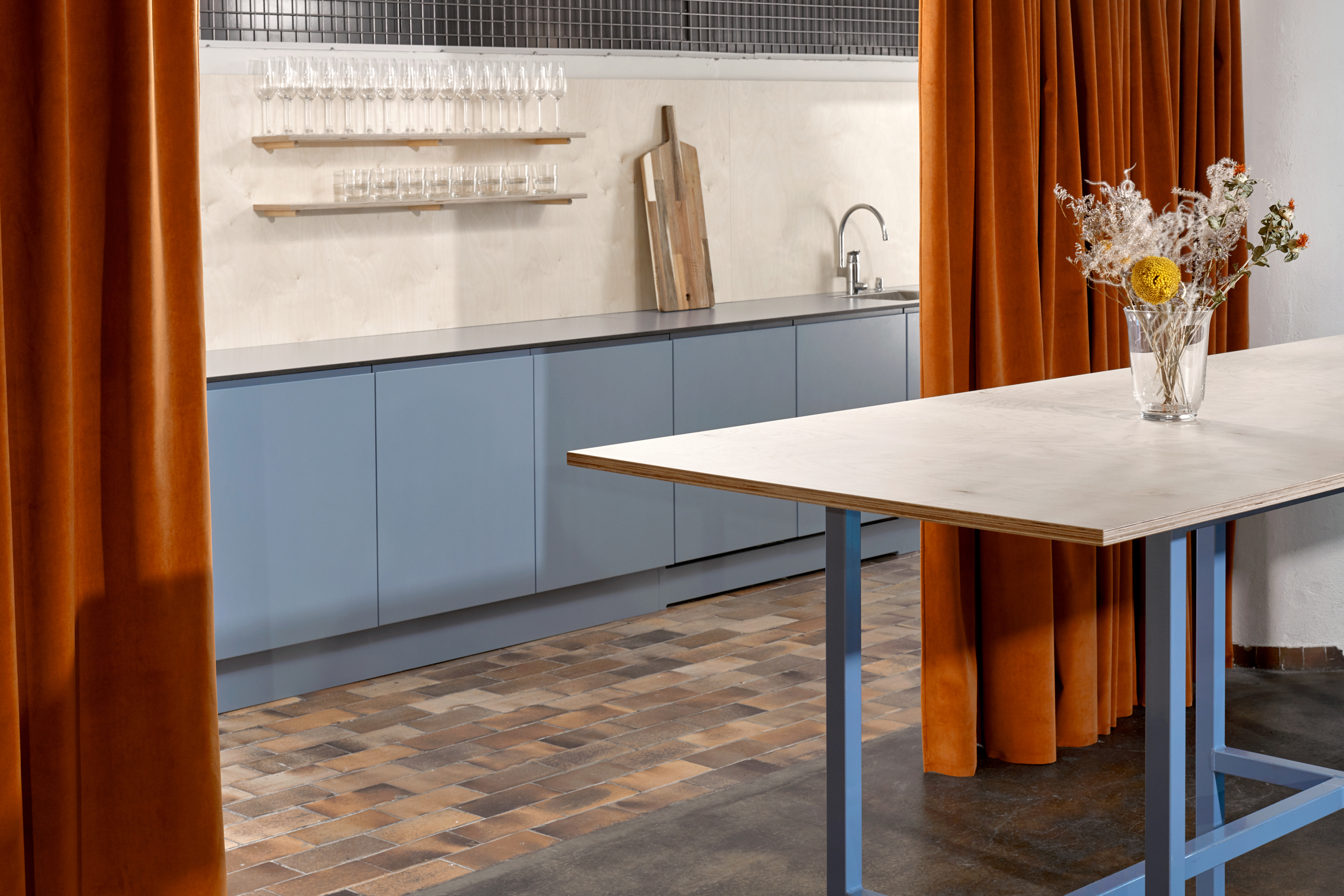 a baby blue kitchen cabinets behind orange curtains, stylish modern look of an interior