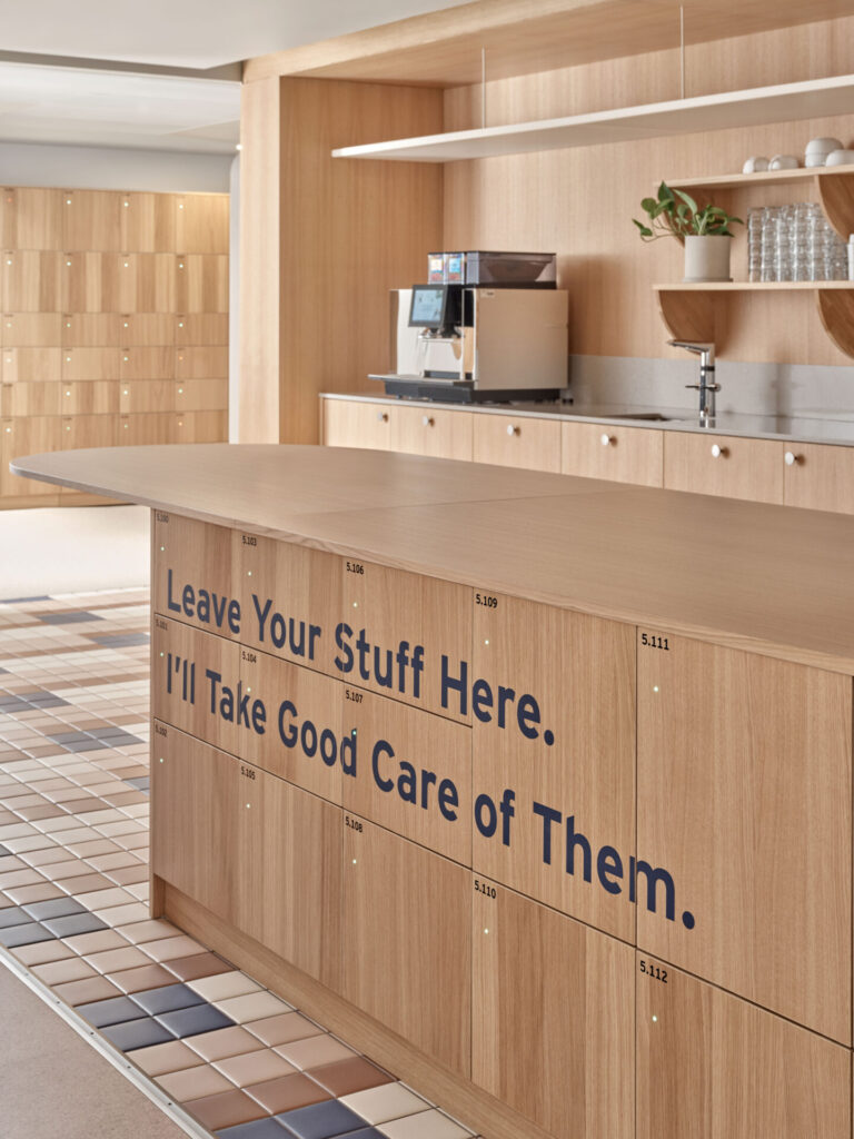oak kitchen counter with integrated storage and typography in dark navy blue saying "leave your stuff here I'll take good care of them"