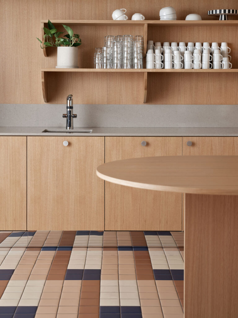 oak kitchen facades colorful tiled flooring, of terracotta, beige and dark blue tiles, coffee cups on the shelves