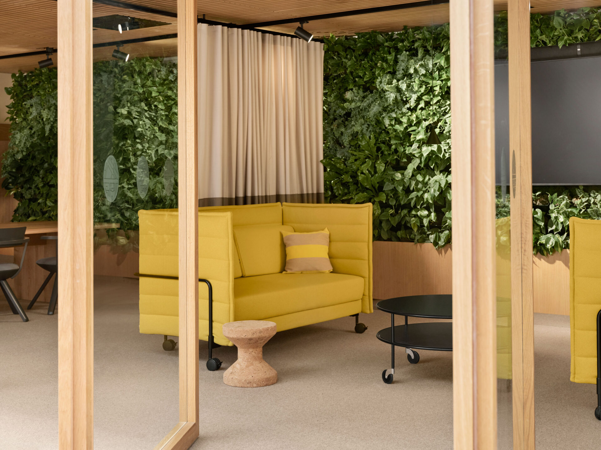 a bright yellow sofa in front of a biophilic wall, modern office design